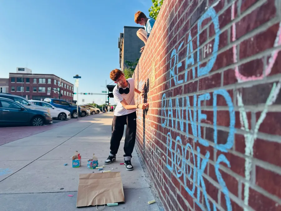 Luke writing 'read banned books' on the chalk wall.