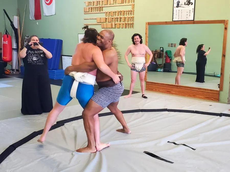 Jared and another member wrestle, smiles on both of their faces.