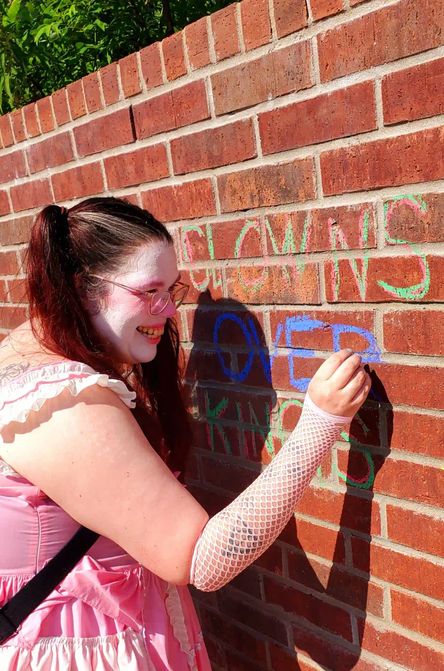 A clown with a mischevious grin draws on the wall