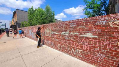 Man with skateboard writing on the wall.